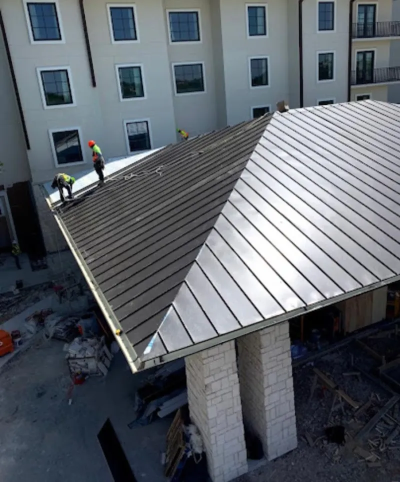 Crew installing standing seam metal roof panels on a commercial project in Cedar Lake